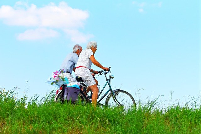 dos personas adultas en bicicleta por un prado